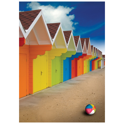 A bright colorful row of summer beach huts on the sand with deep saturated blue sky. Beach ball on sand.